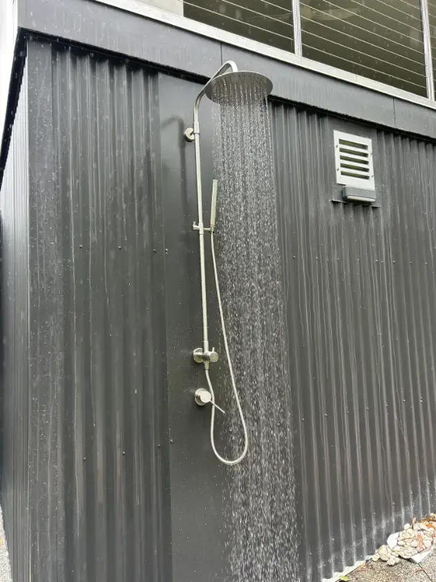 Outdoor shower installed on dark exterior cladding