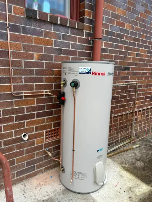 Rinnai hot water cylinder installed against an exterior brick wall
