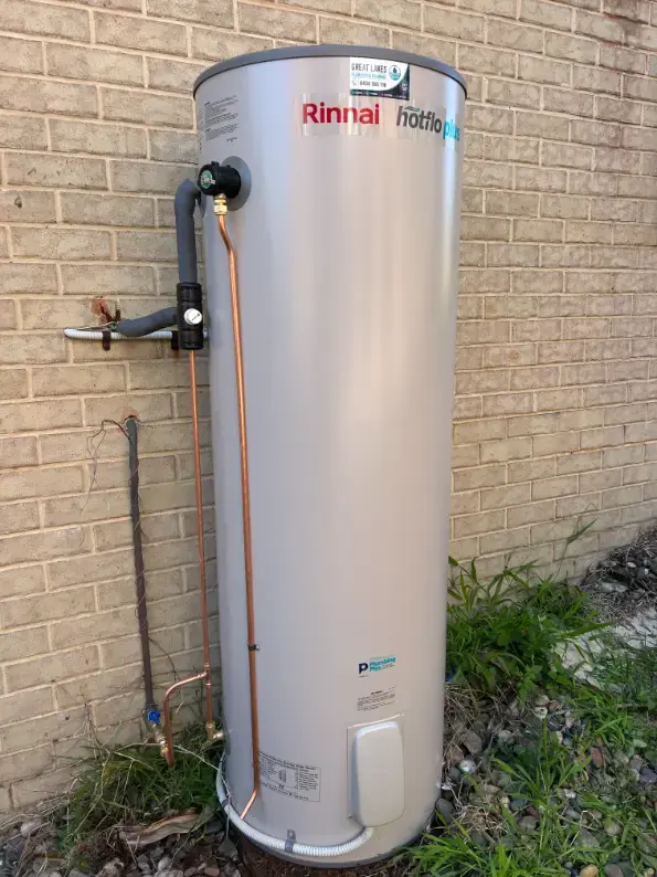 Rinnai hot water cylinder installed on a concrete base beside a brick wall