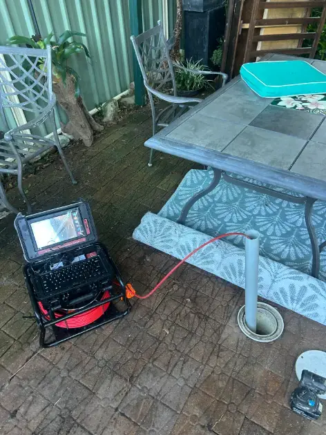 CCTV drain inspection monitor and cable reel set up beside an outdoor drain